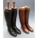 A pair of vintage black leather riding boots with wooden trees and a similar brown leather pair