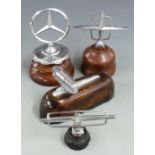 Four various car mascots including Lincoln Continental and Mercedes, all on wooden display bases,