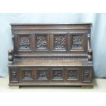 A 19thC carved oak settle, the back with four panels decorated with tavern scenes surrounded with