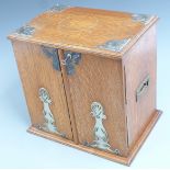 Art Nouveau oak smoker's cabinet with silver plated fittings, the doors opening to reveal three