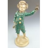 A late 19th/20thC painted metal figure of a young musician with mandolin giving a two fingered