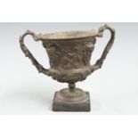 Spelter miniature twin handled vase or urn with mask and foliate decoration, on square slate or