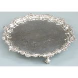 Georgian hallmarked silver salver with scrolling edge and engraved decoration, raised on three