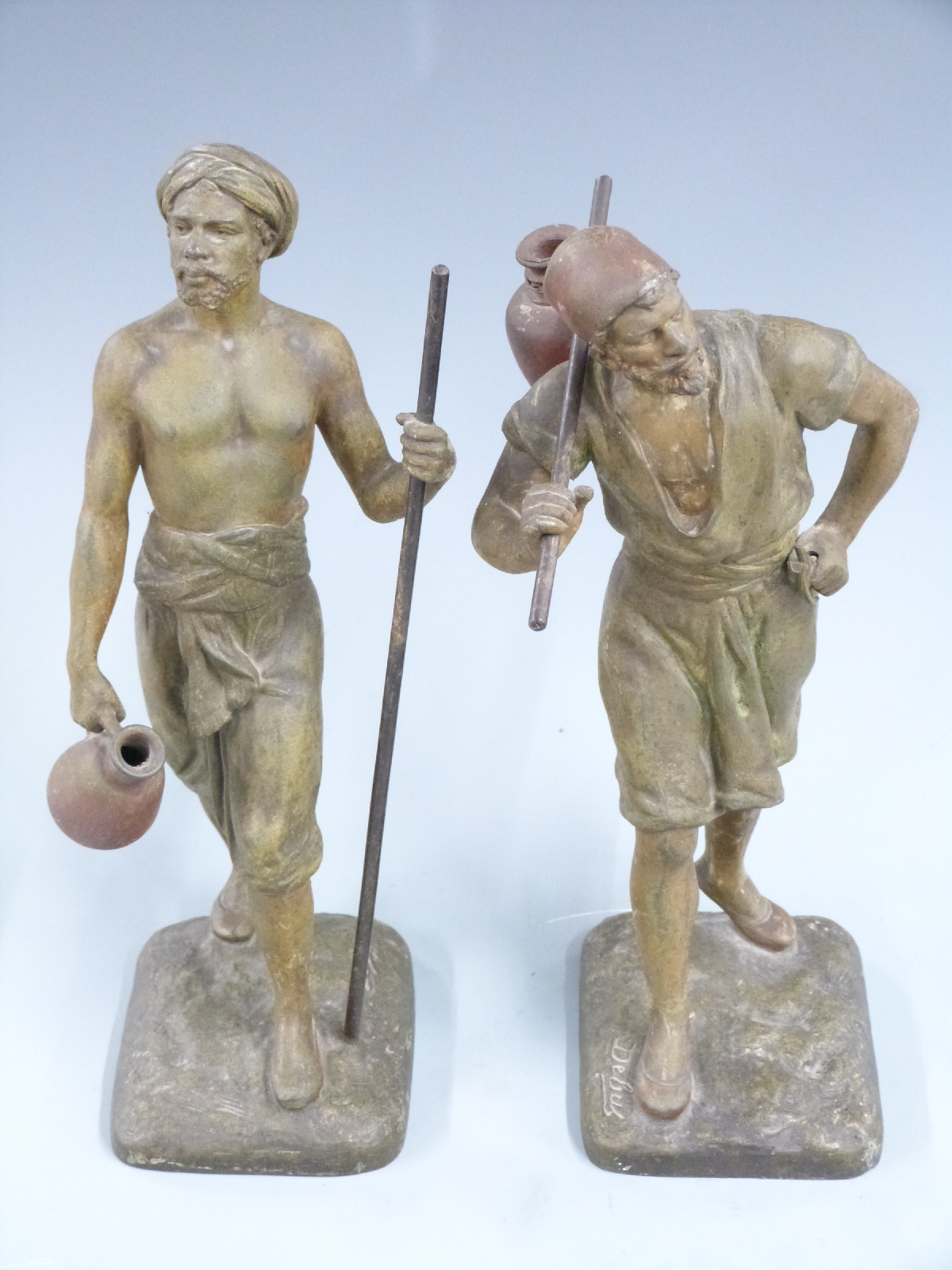 Pair of spelter models of men carrying water after Marcel Debut, signed to base, H31cm
