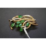 A 14k gold floral brooch set eight jadeite stones, 5cm, 7g total weight.