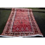 A Persian rug, having fifteen medallions to central field with floral design with geometric and