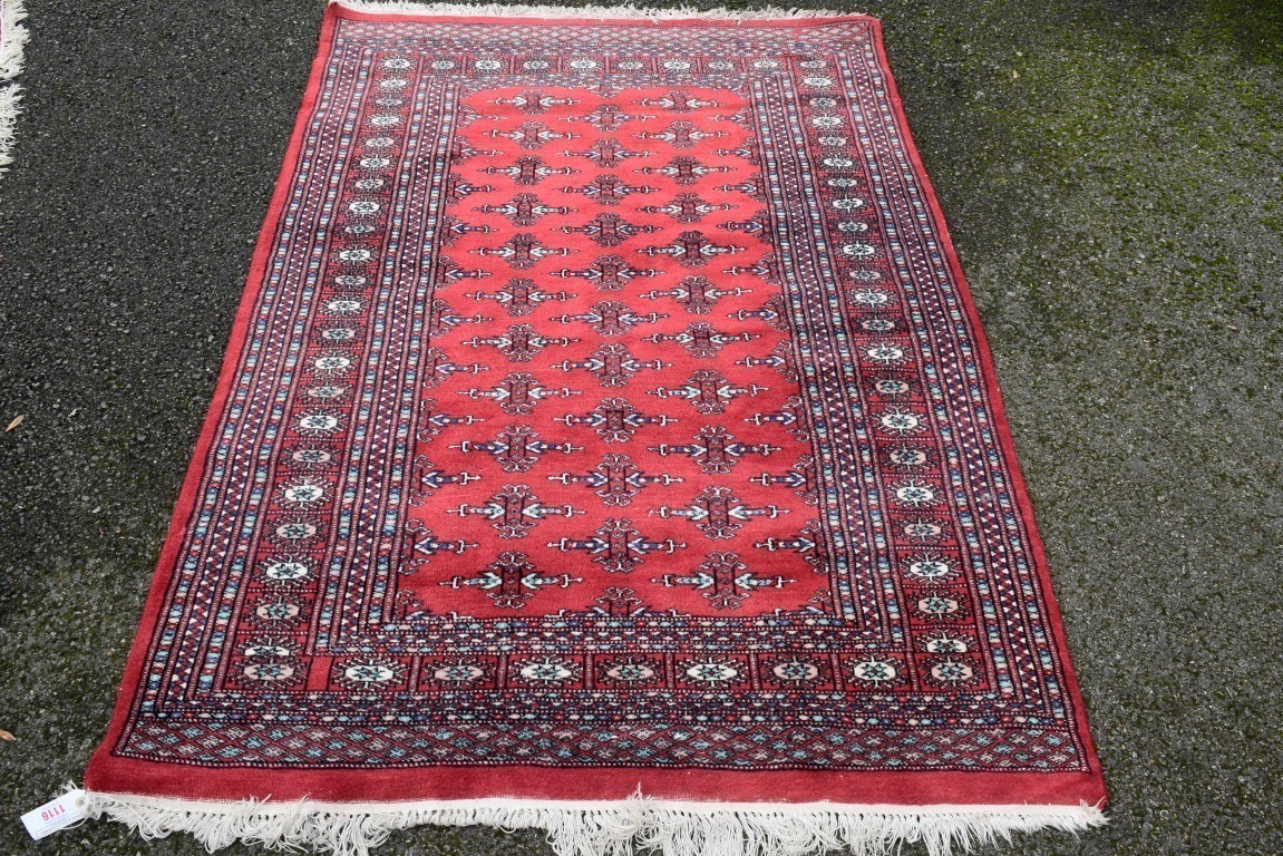 A Pakistani rug, having allover floral and geometric design on a red ground; together with a similar
