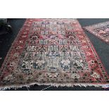 A Persian carpet, having tree and floral design to central field with a floral and geometric border,