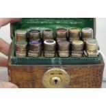 An unusual cased set of twelve glass scent flasks having silver and enamel hinged lids, by Alexander