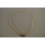 A string of graduated pearls, having an unmarked diamond set clasp.