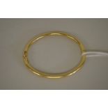 A gold hinged bangle stamped 750, 7.9g.