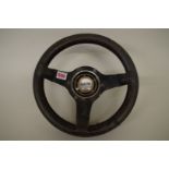 A vintage 12in steering wheel, with black leather rim and 'Cortina' boss.