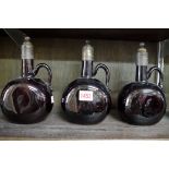 Three antique brown glass and mounted decanters, 21.5cm high.