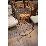 A pair of wrought iron garden chairs, one with arms.
