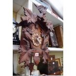 A carved wood cuckoo clock, with two pine cone weights and pendulum.