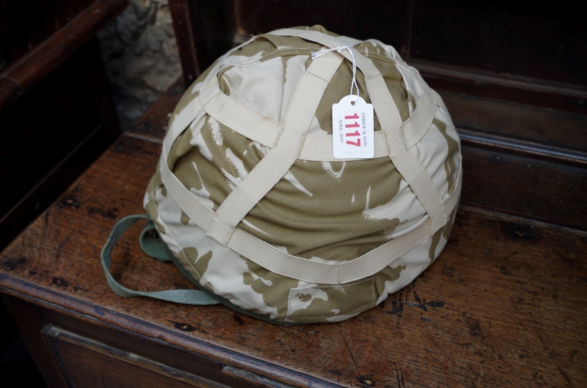 A military helmet, with camouflage cover.