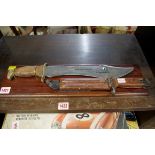 A large dagger mounted on wood plinth; together with a US bayonet and sheath.
