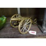 An old brass desk cannon, on two wheel carriage, 24cm long.