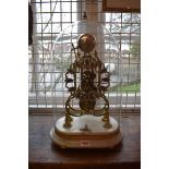 A Victorian brass skeleton clock, with fusee and bell strike, on white marble base, and with glass