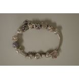 A .925 Pandora charm bracelet with eleven charms and safety chain attached, 63.5g.