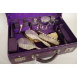 A purple leather travelling case, containing silver topped travelling accessories, London 1912/3,