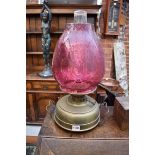 A brass and cranberry glass oil lamp.Â