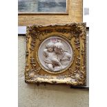 A reconstituted relief moulded marble plaque of cherubs,Â 17cm diameter.