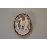 An oval carved shell cameo depicting classical maiden and donkey, having a gold pendant/brooch mount