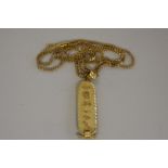 An Egyptian yellow metal hieroglyphic pendant, on an unmarked yellow metal chain, 16.6g.