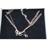 A silver triple colour four strand necklace decorated four pendant hearts, boxed.