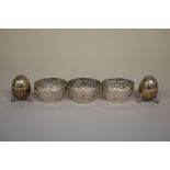 Three Arabic floral chased white metal salts; together with a pair of metal pepperettes.