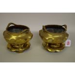 A pair of Chinese brass twin handled tripod censers and covers, 17cm wide.