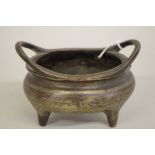 A Chinese bronze twin handled tripod censer,Â sixteen character mark to base, 12cm wide, 702g.