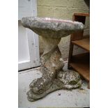 An old weathered composition stone bird bath, with dolphin support, 49cm high.
