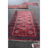 A Baluch rug, having repeated design to central field with animal motifs on a red ground, 288 x