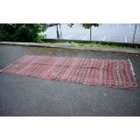 A Baluch carpet, having geometric design on a red ground, 366 x 135cm.