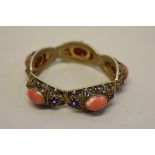 A gilt metal filigree hinged bracelet, set five oval cabochon corals and decorated with blue enamel,