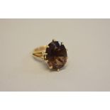 An oval topaz in unmarked mount, the shank a hallmarked 22ct wedding band.