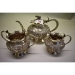 An Indian white metal three piece teaset, heavily decorated with native scenes, having elephant