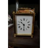A brass carriage timepiece, height including handle 12cm, with leather travel case and winding key.