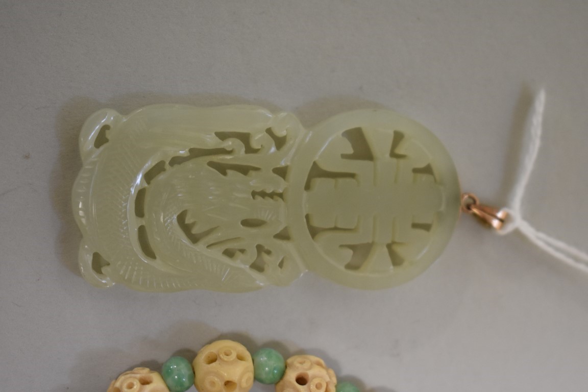 A Chinese carved and pierced celadon jade pendant, decorated with a dragon, 5.8cm high, the yellow - Image 2 of 3