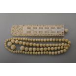 A Chinese carved ivory cribbage marker, 17.5cm long; together with an bone bead necklace. (2)