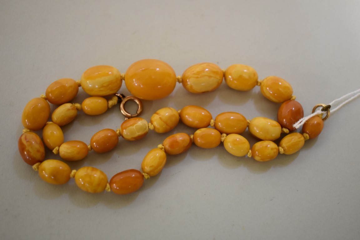 A 'butterscotch' amber bead necklace, of twenty nine oval graduated beads, with unmarked yellow