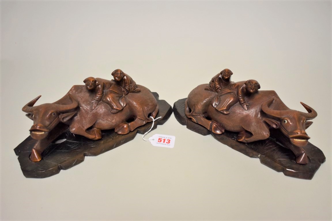 A pair of Chinese carved wood buffalo figure groups, late 19th century, each recumbent animal with