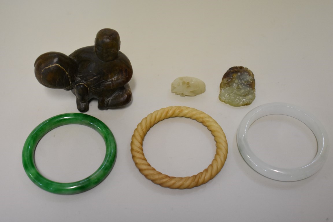 A small group of Chinese jade, comprising: three bangles, on with wrythen decoration, a carved