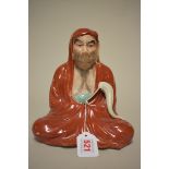 A Japanese porcelain seated figure of Bodhidharma, Meiji, 21.5cm high.