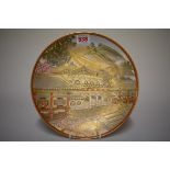 A Japanese Satsuma pottery plate, Meiji, painted with a temple, 25cm diameter
