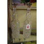 A pair of cut glass and silver mounted bottles and stoppers.