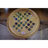 A collection of thirty two glass marbles, on solitaire board.