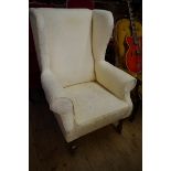 An antique damask upholstered wing armchair.